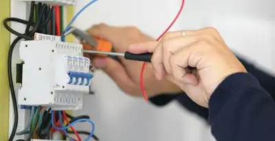 Electrician installing and adjusting circuit breakers in an electrical panel in Des Moines, IA