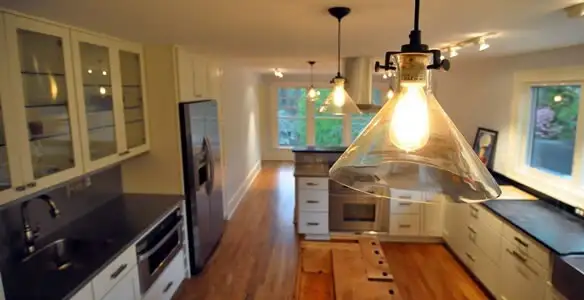 Residential electrician installing modern indoor light fixture in a home in Des Moines, IA