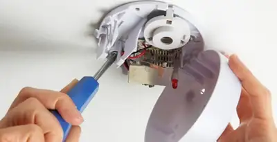 Certified technician wiring smoke detector during installation in Des Moines, IA